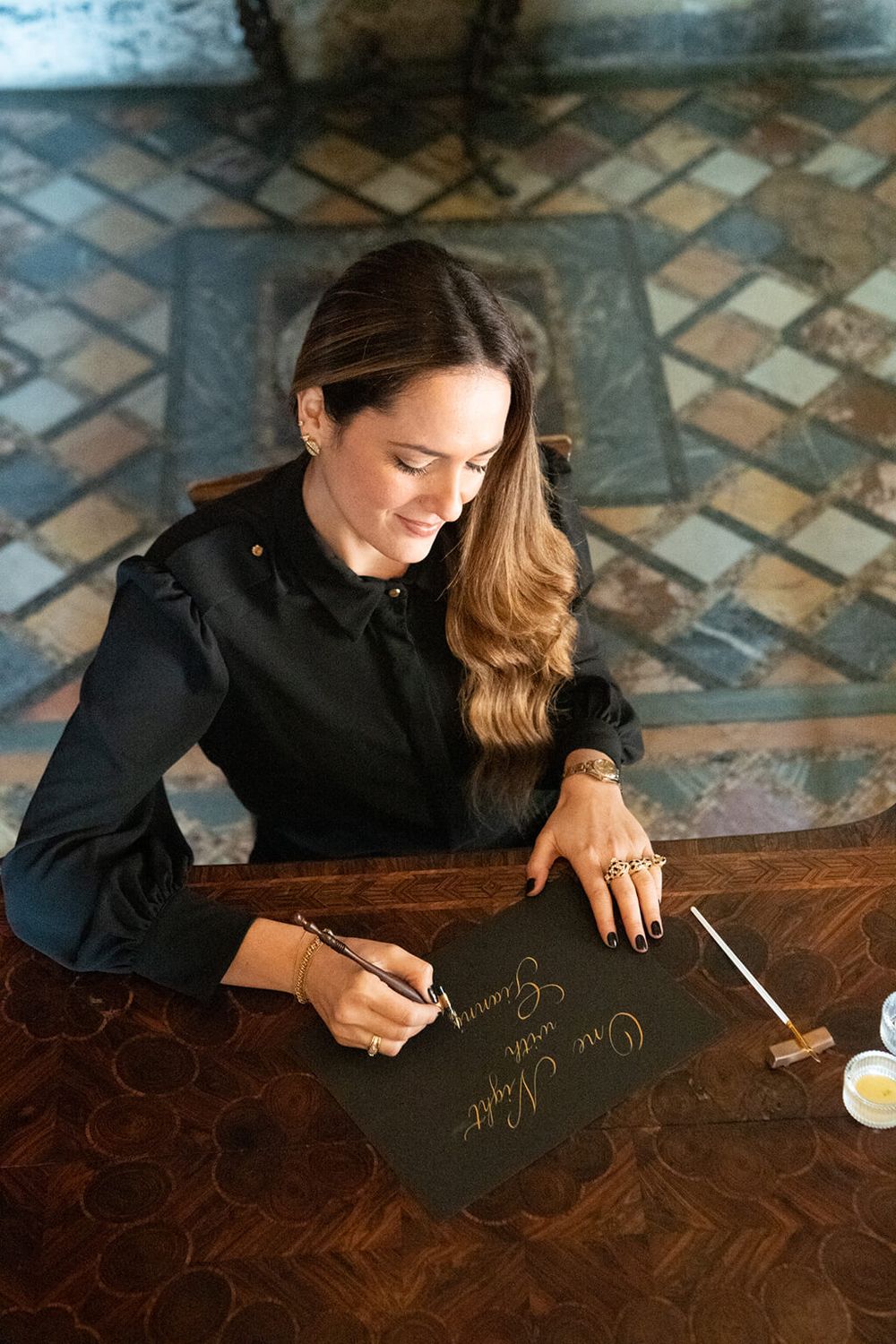 Veronica Di Salvo scrive a mano con pennino e inchiostro oro su carta nera